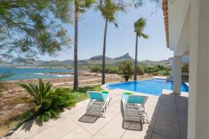 eine Terrasse mit Stühlen, einem Pool und Palmen in der Unterkunft Es Tamarells -S'Estanyol- in Colònia de Sant Pere