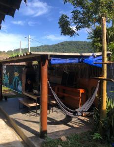 un hamac à l'extérieur d'une cabane avec une personne assise dedans dans l'établissement Macondo Hostel Itamambuca, à Praia de Itamambuca