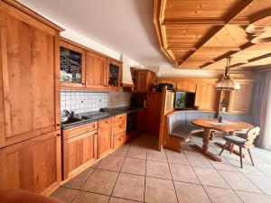 Una cocina con armarios de madera, una mesa y un fregadero. en Traditional Cozy Apartment, en Tirolo 7 fotos más