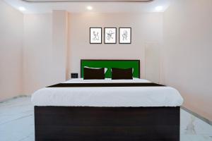 a bedroom with a large bed with a green headboard at Hotel O K2 Lodging And Boarding in Nagpur