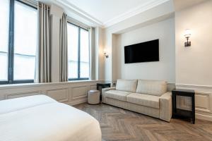 a bedroom with a bed and a couch and a tv at Hôtel Perreyve - Jardin du Luxembourg in Paris