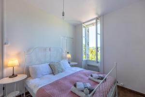 - une chambre blanche avec un lit et une couverture rose dans l'établissement Welcome to No5, à Sarlat-la-Canéda