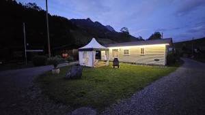 a small house with a tent in the grass at Mobilehome in Weissenburg