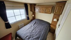 a small bedroom with a bed and a window at Mobilehome in Weissenburg