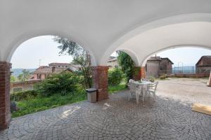 a patio with a table and chairs under an archway at Vacanza Nel Cuore Del Monferrato in Rocca Grimalda