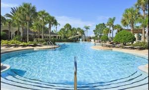 a large swimming pool in a resort with palm trees at 3 Bedroom Condo with Water Park & Fantastic Pool only Minutes To Walt Disney World's Front Gate!!! in Orlando