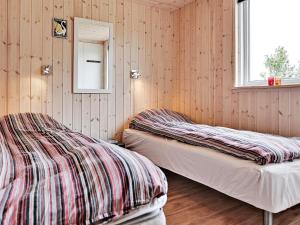 two beds in a room with wooden walls and a window at Luxury Retreat with Pool - By Traum Ferienwohnungen in Bogense