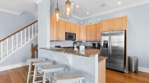 a kitchen with a stainless steel refrigerator and wooden cabinets at Three Herons Roost by Emerald Coast Retreats in Sunnyside