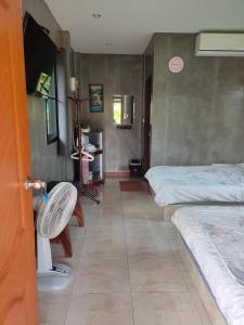 a room with two beds and a table and a door at Ban Rim Nam Klongwan in Klong Wan