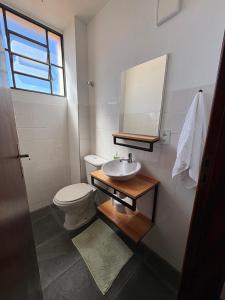 Un baño con inodoro, lavabo y espejo. en Loft charmoso bem no centro, en São Sebastião