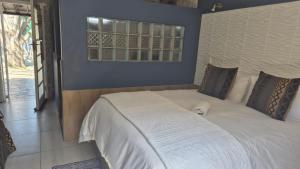 a bedroom with a large white bed with a window at 44 on Ennis Guest Lodge and Restaurant - in Ermelo