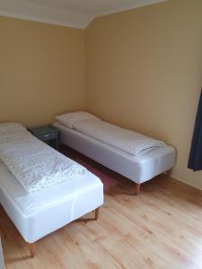two beds in a small room with wooden floors at Feriehus med utsikt mot fjellet Hoven in Smedvik