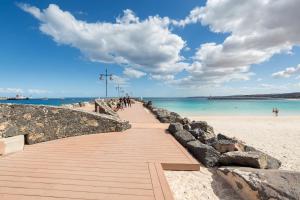a boardwalk on a beach with people walking on it at Home2Book Modern Apartment Near Playa del Pozo in Puerto del Rosario