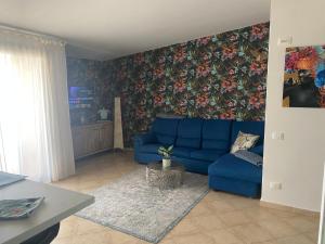 a living room with a blue couch and floral wallpaper at Tropical Anzso in Santa Maria