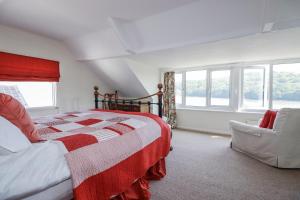 a bedroom with a red and white bed and a chair at Kiln Cottage in Fowey