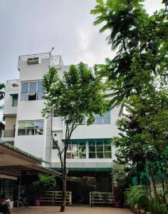 Un edificio blanco con un árbol delante. en URBAN COTTAGE, en Guwahati