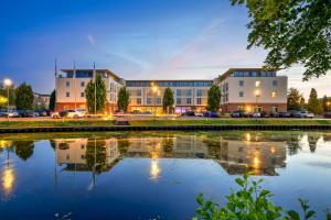 a building with a reflection in a body of water at Best Western Plus Hotel Papenburg in Papenburg