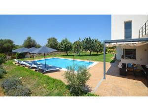 ein Swimmingpool mit Stühlen und Sonnenschirmen neben einem Haus in der Unterkunft Country House in Binissalem with Pool in Binissalem