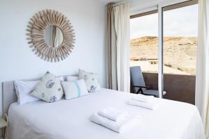 a bedroom with a white bed with a mirror on the wall at Seaside Home Jacuzzi Pool Free Surf Retreat in El Médano +57 photos