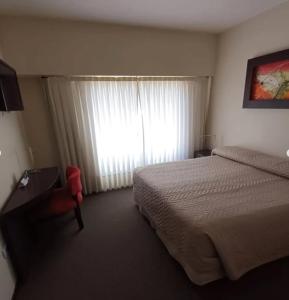a hotel room with a bed and a window at Hotel Amucan in Neuquén