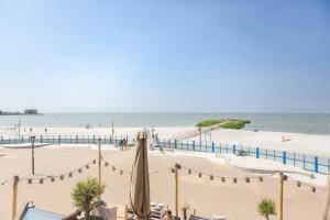a view of a beach with an umbrella and the ocean at Zuiderzee State - Appartementen in Makkum