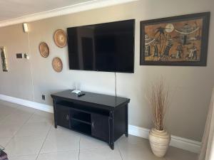 Una sala de estar con un televisor de pantalla plana en una pared. en Seaview Apartments -Near MSC Cruise Terminal and UShaka Marine, en Durban