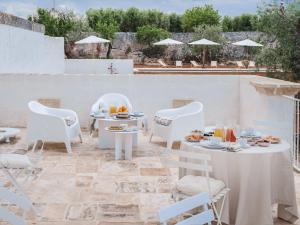 a patio with white chairs and tables with food on it at GH Masseria Monet in Monopoli