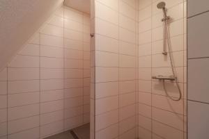 a shower in a bathroom with white tiles at Beachvilla XL - 12 personen in Holle Poarte +8 photos
