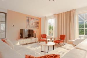 a living room with a white couch and a tv at Beachvilla Royaal met Sauna - 10 personen in Holle Poarte