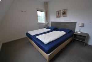 a bedroom with a bed with blue sheets and a window at Beachvilla Royaal Classic met Sauna - 10 personen in Holle Poarte