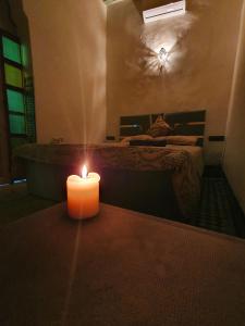 a candle in a room with a bed and a tub at Backpackers Riad in Fès