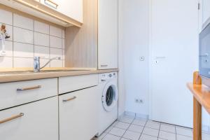 a white kitchen with a sink and a washing machine at Sünnslag Wohnung 049 in Boltenhagen