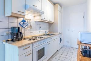 a kitchen with white cabinets and a stove top oven at Sünnslag Wohnung 049 in Boltenhagen