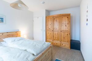 a bedroom with a bed and a wooden cabinet at Sünnslag Wohnung 049 in Boltenhagen +12 photos
