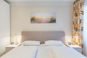 a bedroom with a white bed and a painting on the wall at Sünnslag Wohnung 113 in Boltenhagen