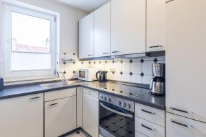 a kitchen with white cabinets and a stove top oven at Sünnslag Wohnung 113 in Boltenhagen +21 photos
