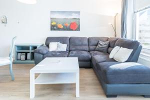 a living room with a blue couch and a white table at Sünnslag Wohnung 114 in Boltenhagen