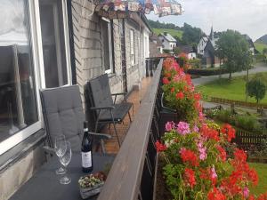 a balcony with a bottle of wine and two chairs and flowers at Gemütliche Wohnung für 4 Personen in Medebach