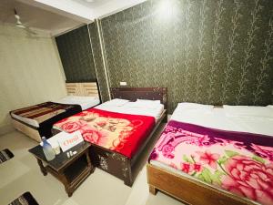 a room with two beds and a table in it at Omji - Shri Ram Janki Ashram, 20 min walk to Ram Janmabhumi Temple in Ayodhya +37 photos