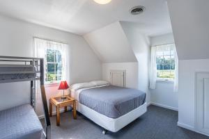 a white bedroom with a bed and two windows at Country Cottage in Apple Creek