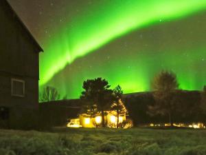 an aurora over a house in a field at 6 person holiday home in Storsteinnes in Storsteinnes