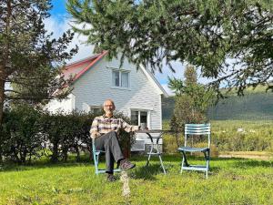 a man sitting at a table in front of a house at 6 person holiday home in Storsteinnes in Storsteinnes