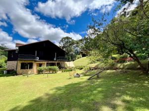 a house in a field with a grass yard at Casa 03 Vale Boa Vista - Charme Rústico em Condomínio com Área de Lazer Completa in Teresópolis
