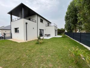 a white house with a black roof on a yard at Villa LOM, 800 m de la plage in Asnelles