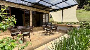 a patio with chairs and tables and a glass roof at Casa 03 Vale Boa Vista - Charme Rústico em Condomínio com Área de Lazer Completa in Teresópolis +36 photos