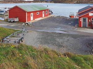 a red building and a boat yard next to the water at 6 person holiday home in Oksvoll in Oksvoll