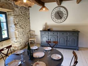 a dining room with a table and a clock on the wall at La Maison de Dom in Beaulieu-sur-Dordogne