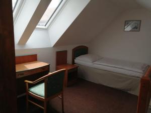 ein kleines Zimmer mit einem Bett, einem Schreibtisch und einem Fenster in der Unterkunft Apartman Reduta in Lučenec