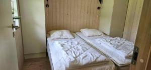 małe łóżko w pokoju z białą pościelą i poduszkami w obiekcie Cozy Cottage Just 300 M From Høve Beach w mieście Asnæs