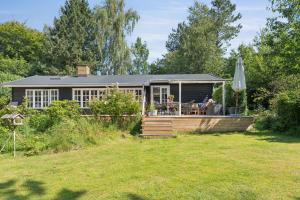 une maison avec une terrasse et un parasol dans une cour dans l'établissement Family-Friendly Cottage Near Beach & Nature, à Vejby
